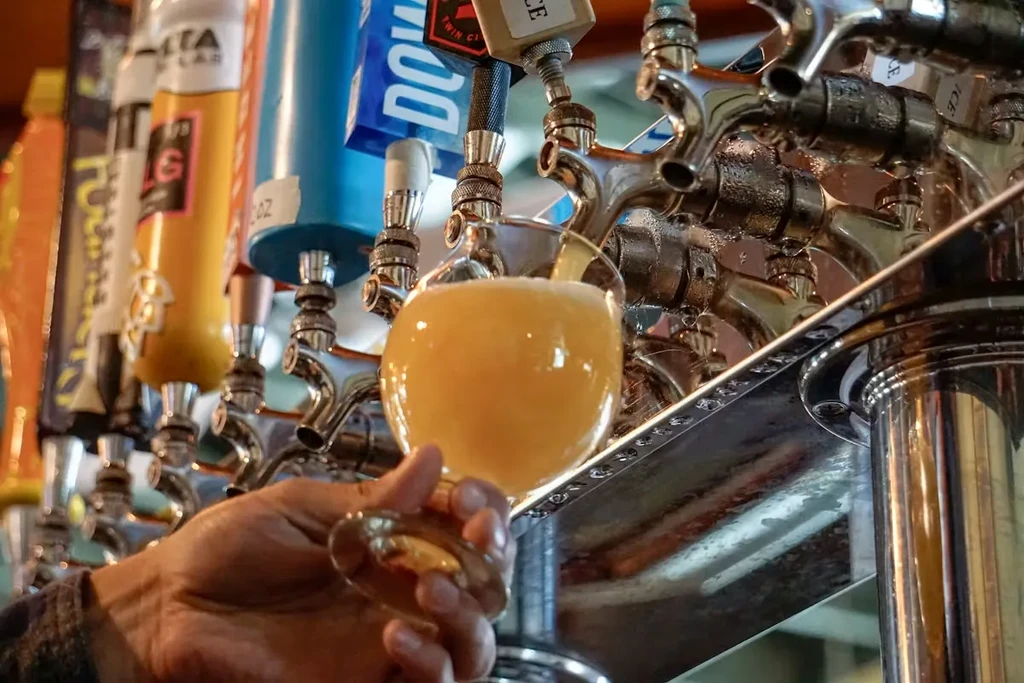 Hazy golden beer being poured into a glass from a tap.
