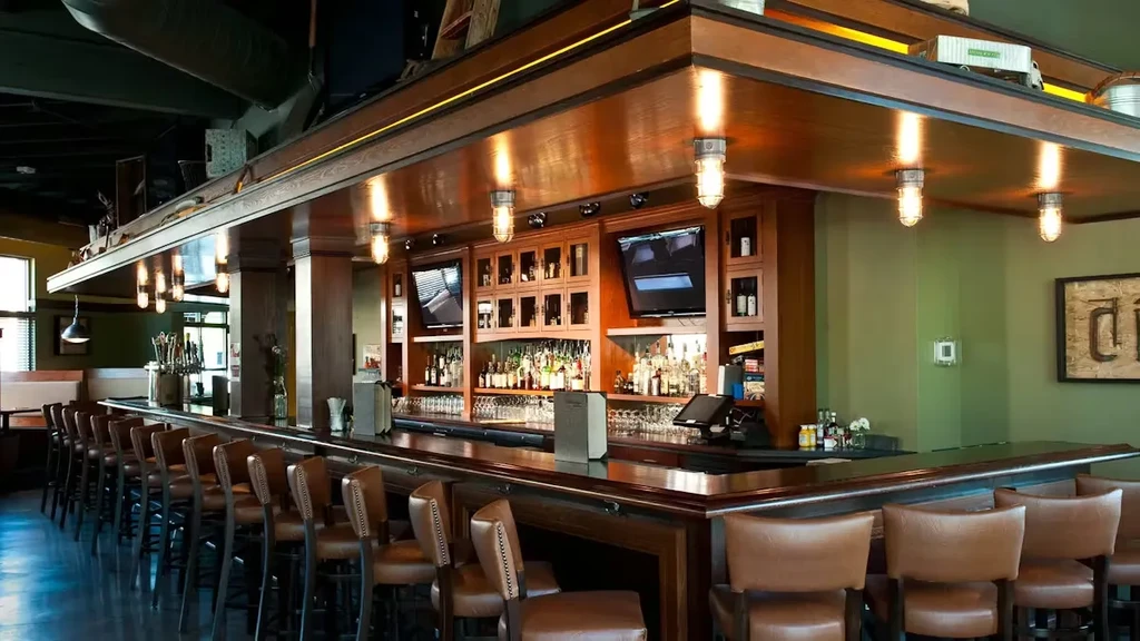 Empty modern rustic bar with dark wood counter and leather stools.