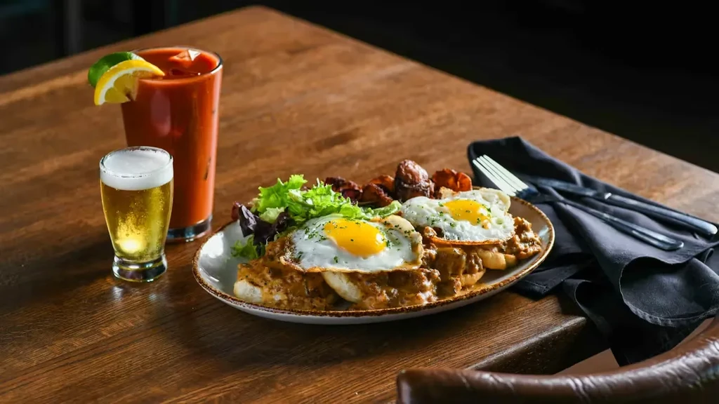 Savory biscuits and gravy with eggs, salad, Bloody Mary, and beer.