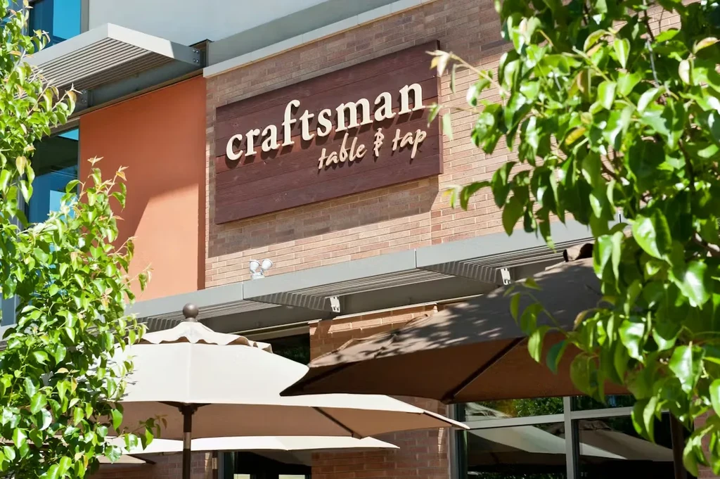 Craftsman Table & Tap building with wood sign, awning, and patio.