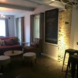 Warm, cozy restaurant lounge with plum seating, chalkboard, and brick pillar.