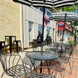 Empty outdoor restaurant patio with dark metal furniture and striped umbrellas.