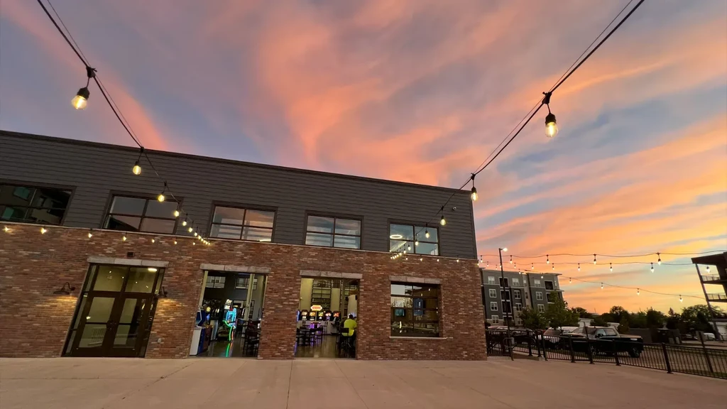Building exterior with string lights under a colorful dusk sky.