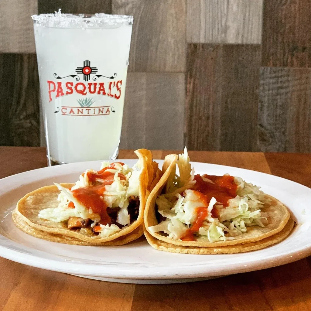 Two tacos with meat, lettuce, red sauce, and a Pasqual's Cantina margarita.