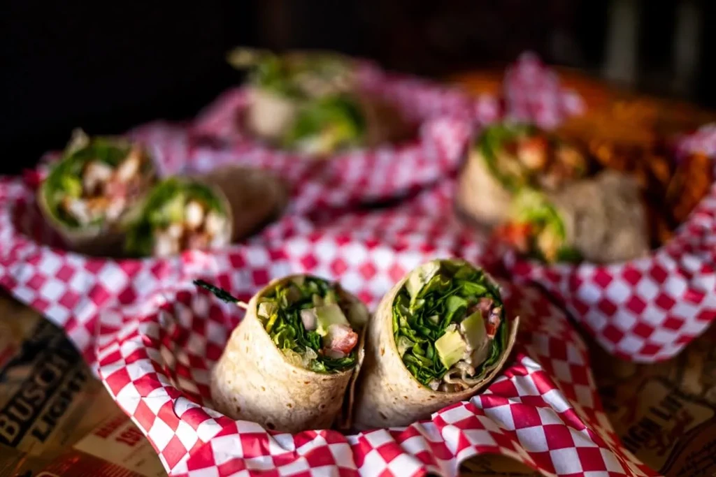 Two wrap halves with lettuce, avocado, and protein in checkered liners.