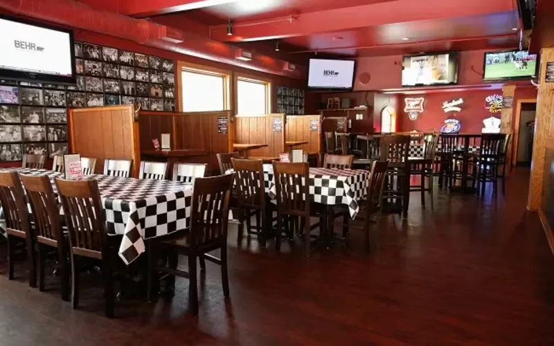 Casual restaurant interior, red walls, dark wood, checkered tablecloths, multiple TVs.