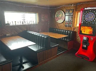 Bar interior with dark booths, wood paneling, and a Bullshooter dartboard.