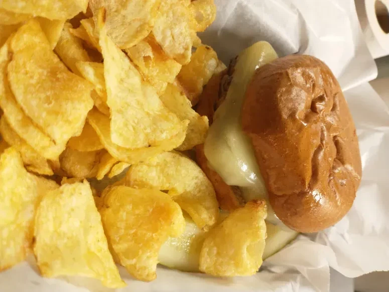 Sandwich with melted cheese and a large pile of golden chips.