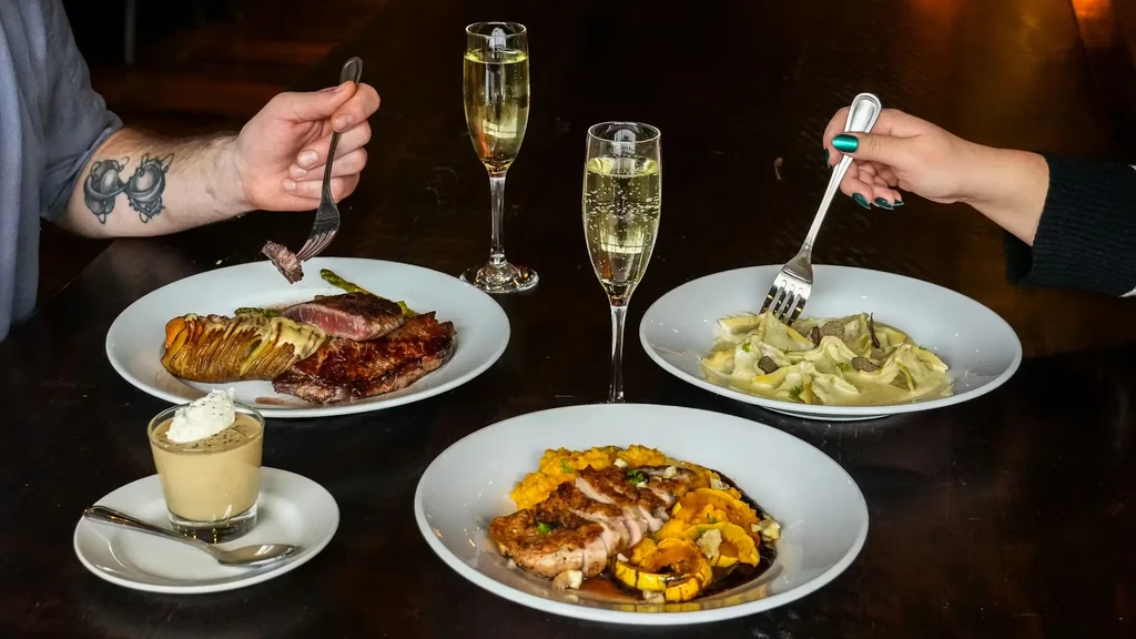 Upscale restaurant table with diverse dishes, champagne, and diners.