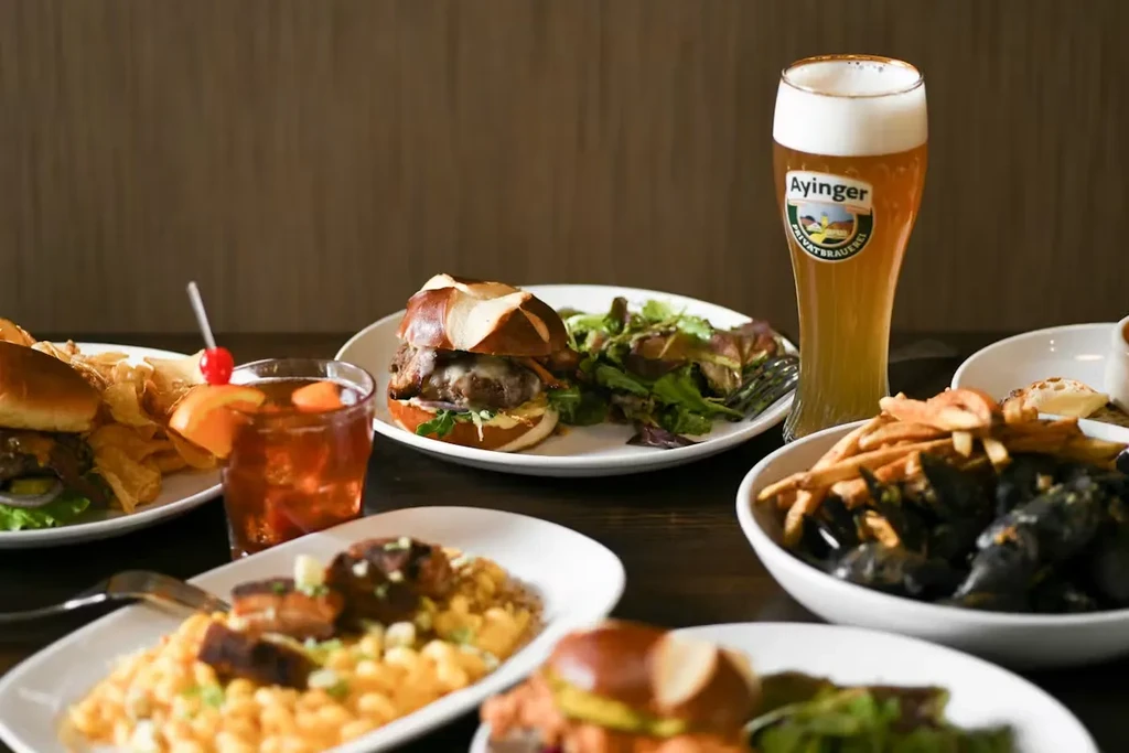 Restaurant table with mac and cheese, burgers, mussels, beer, and cocktail.