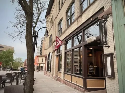 "Madison's" brick restaurant with vertical sign, Wisconsin flag, outdoor patio.