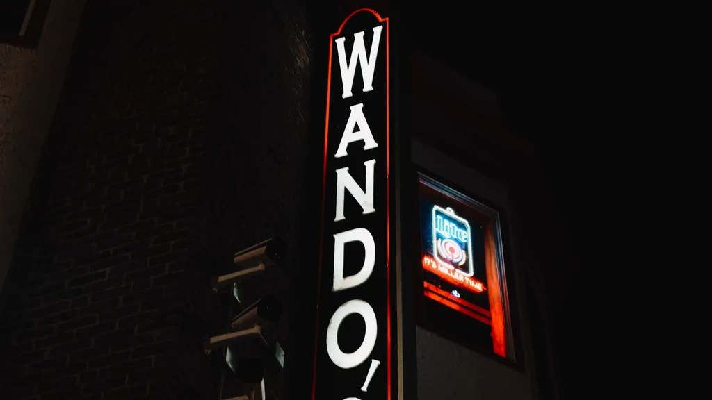 White WANDO'S vertical neon sign and Miller Time sign at night.