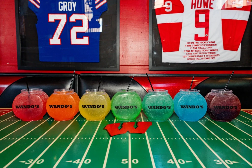 Seven colorful WANDO'S drinks on a football field table with sports jerseys.