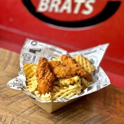 Crispy golden chicken tenders and waffle fries in a paper tray.