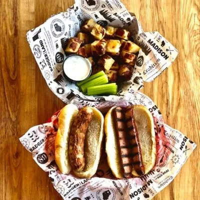 Hot dogs, roasted potatoes, celery, and dip on a wooden table.