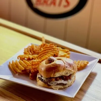 Close-up: Pretzel bun burger with cheese and waffle fries.