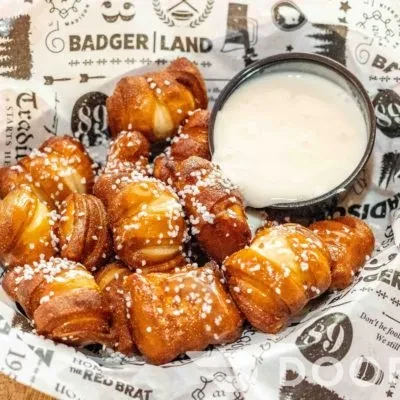 Salted pretzel bites with dipping sauce on 'BADGER LAND' branded paper.