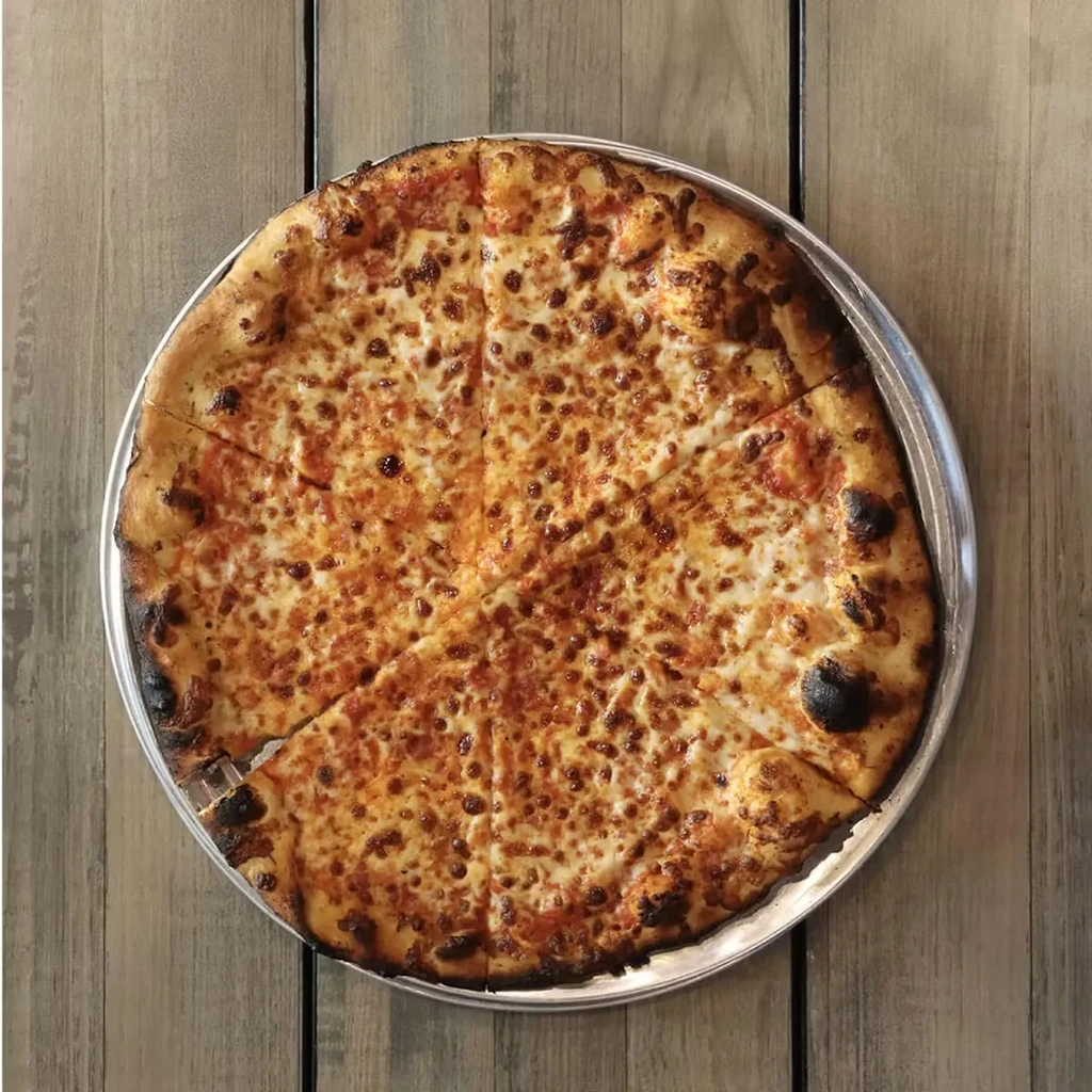 A well-done cheese pizza, sliced, on a pan and wooden table.