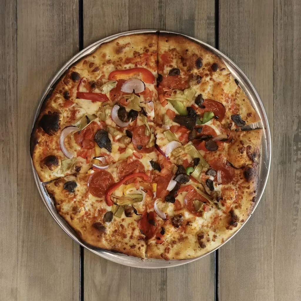 Round pizza with pepperoni, vegetables, and cheese on a silver pan.