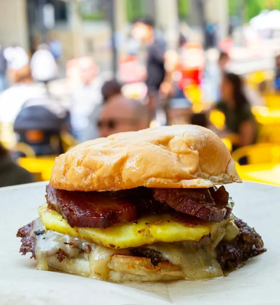 Substantial burger with melted cheese, grilled pineapple, and bacon.