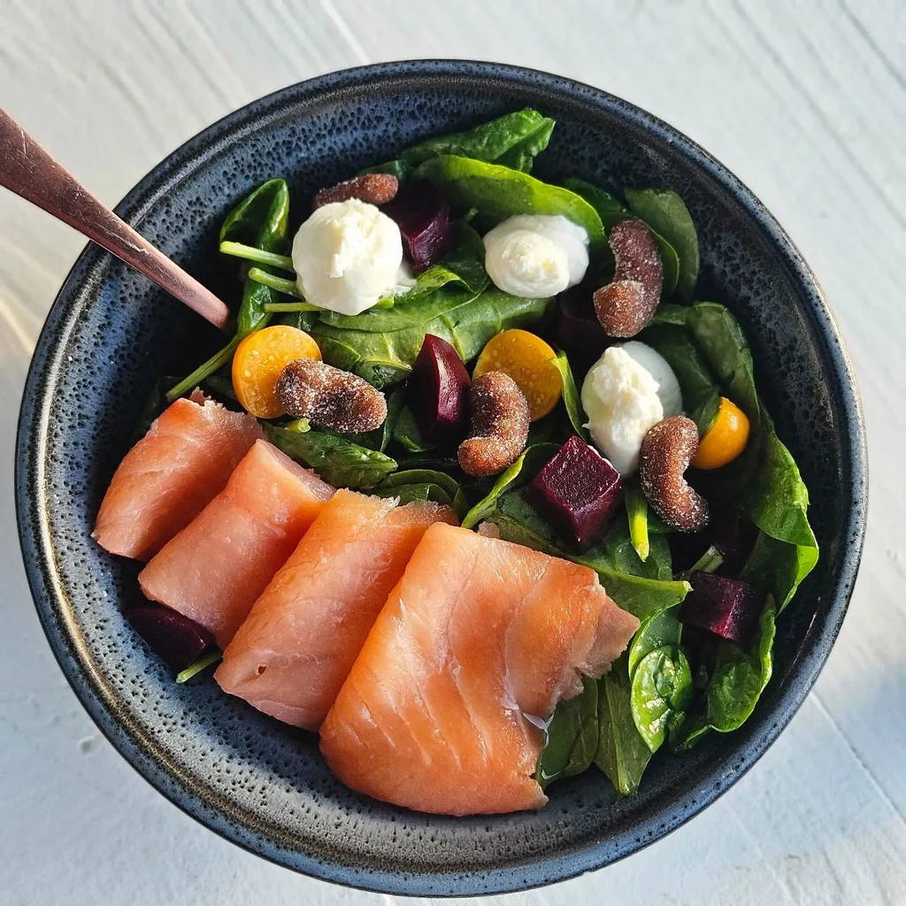 Overhead shot: Salad with salmon, spinach, mozzarella, beetroot, and yellow tomatoes.