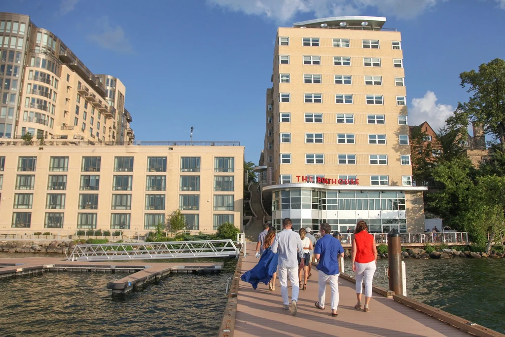 Group walks on wooden pier towards The Boathouse building.