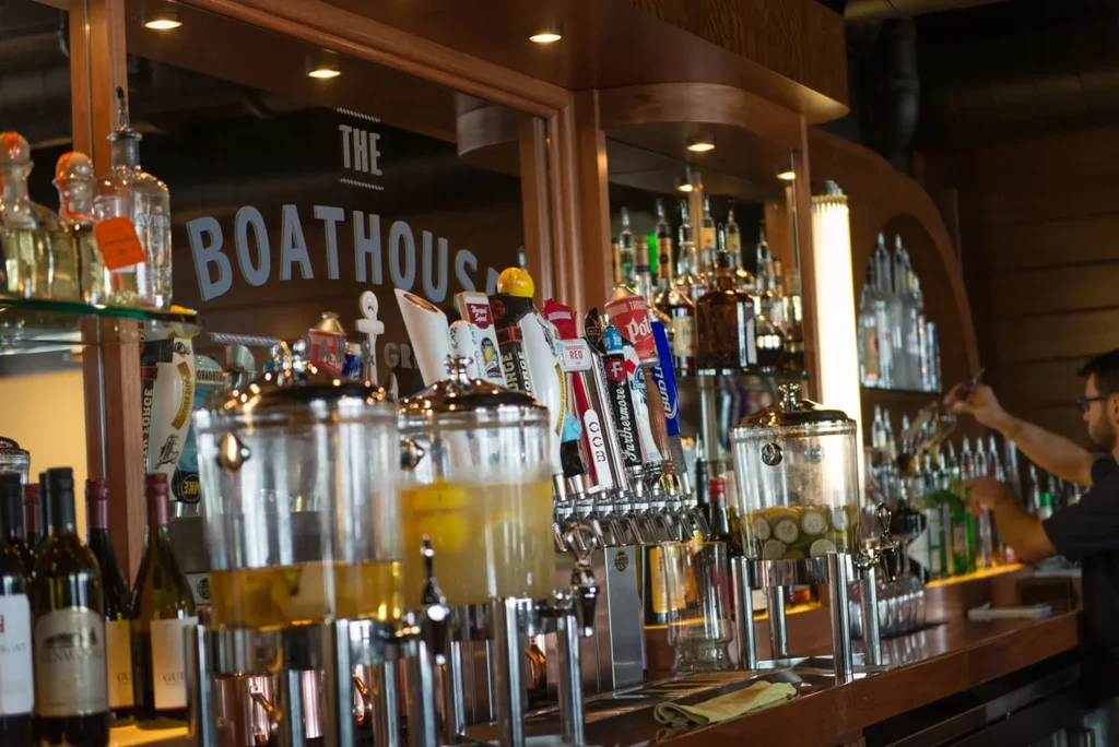 Boathouse bar with beverage dispensers, beer taps, and liquor bottles.