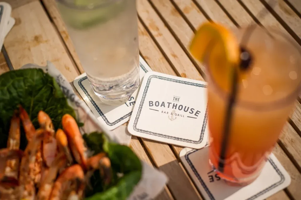 Coaster for The Boathouse Bar & Grill with drinks and shrimp.