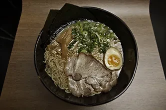 Creamy ramen bowl with chashu, soft-boiled egg, nori, and greens.