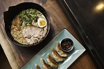 Overhead view of ramen bowl with egg and five pan-fried gyoza.