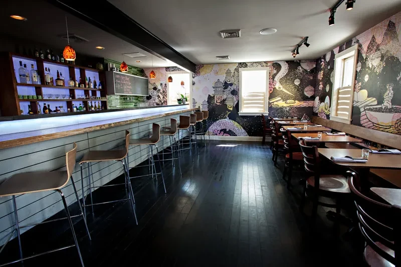 Modern restaurant bar interior with vibrant abstract wall mural.