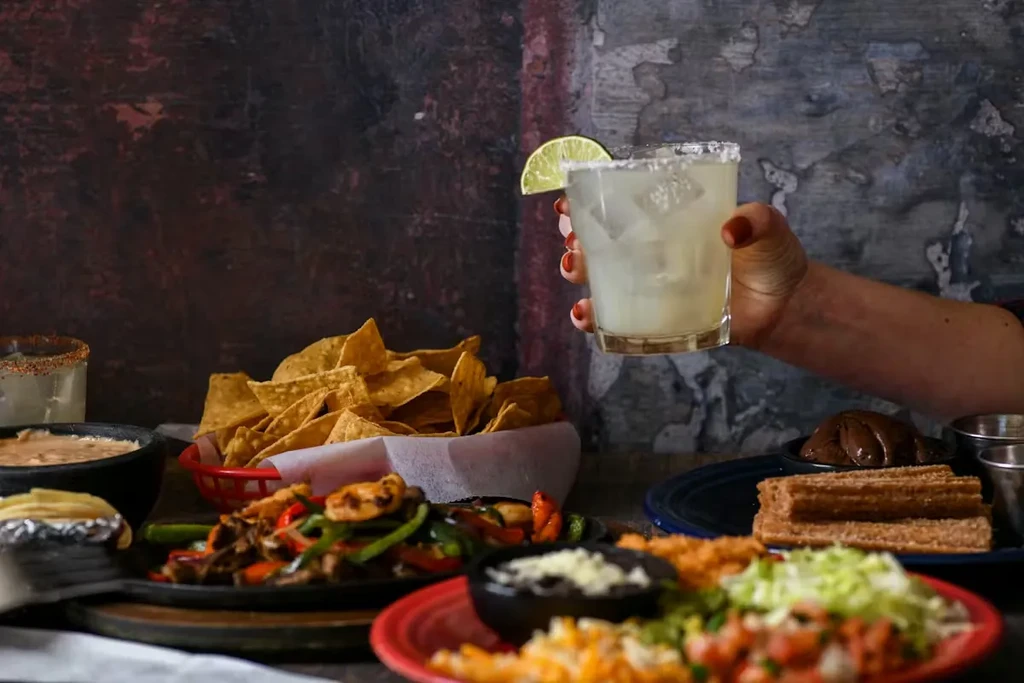 Table laden with Mexican food: fajitas, churros, chips, and margaritas.