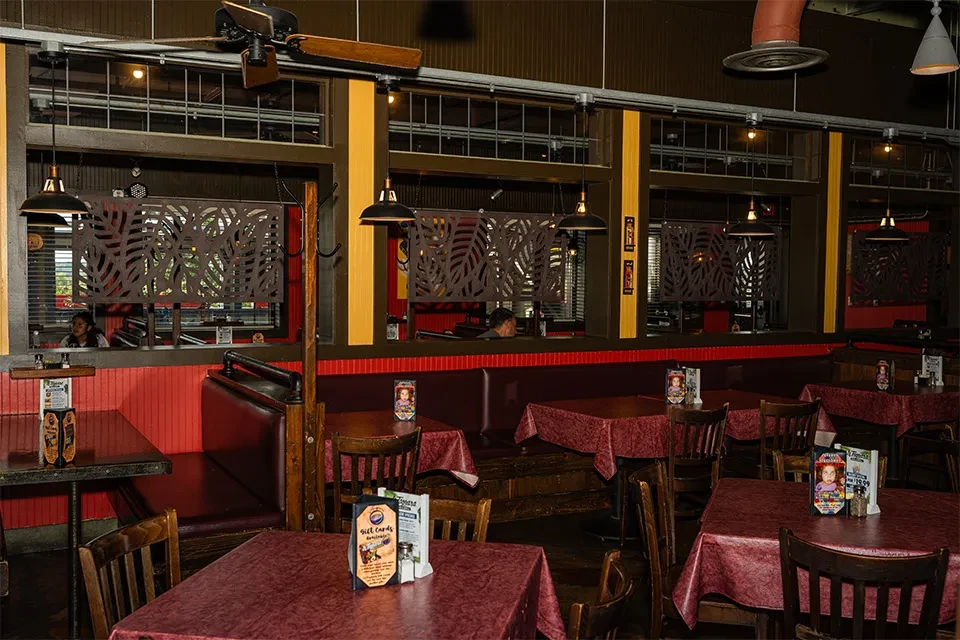 Restaurant interior with deep red booths, dark wood, and industrial lights.