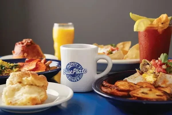 Diverse breakfast spread on a blue table with a Monty's Diner mug.