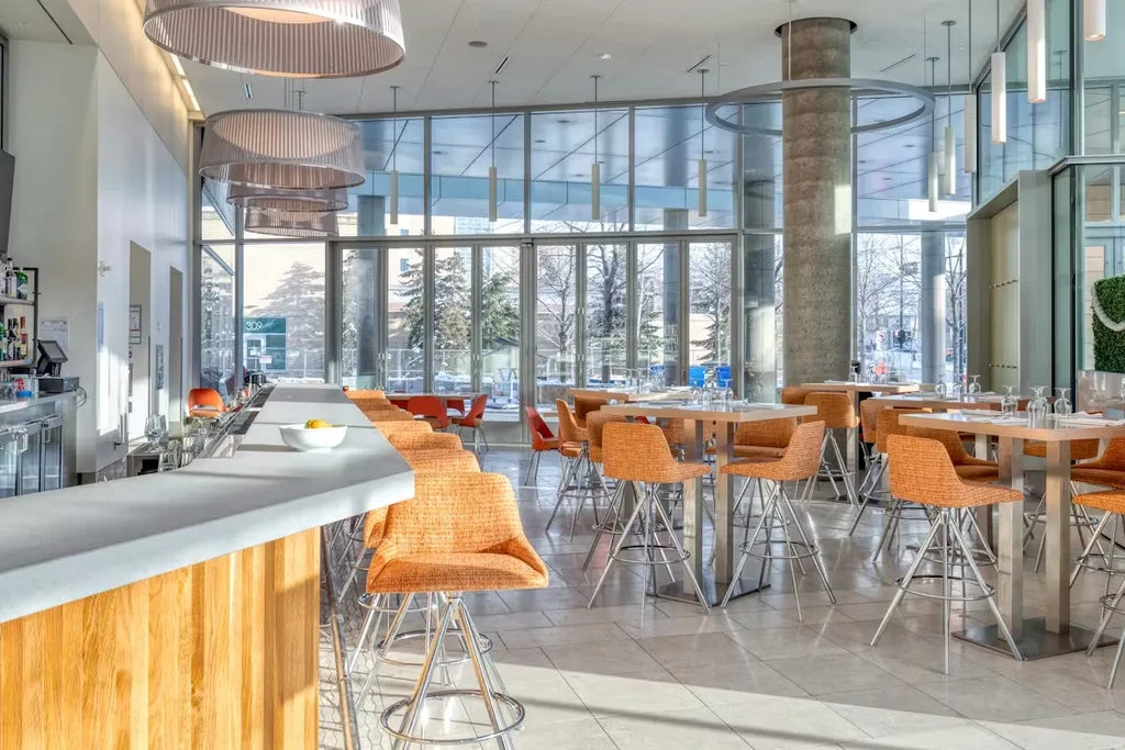 Spacious modern bar and dining area with orange high-top stools.