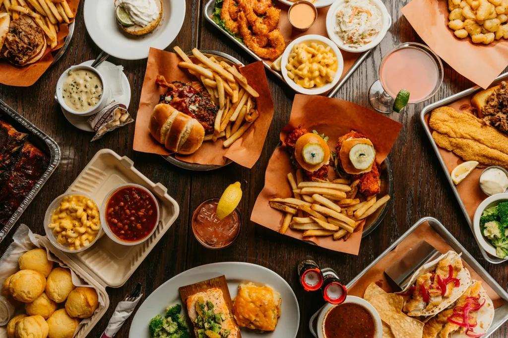 Overhead shot of a spread of fish, chicken, sandwiches, sides, and drinks.