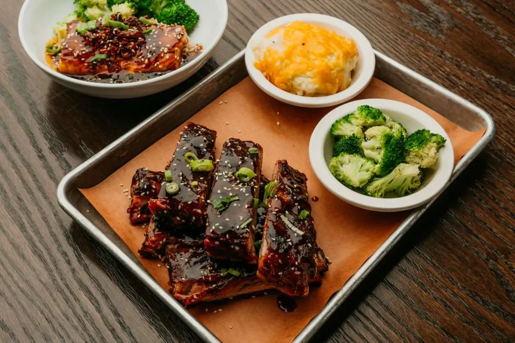 Tray of glazed salmon, ribs, cheesy potatoes, and steamed broccoli.