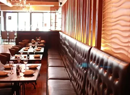 Empty restaurant interior, set tables, brown chairs, tufted leather booth.