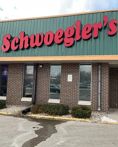 Schwoegler's commercial building exterior with red sign, green metal, and brick.
