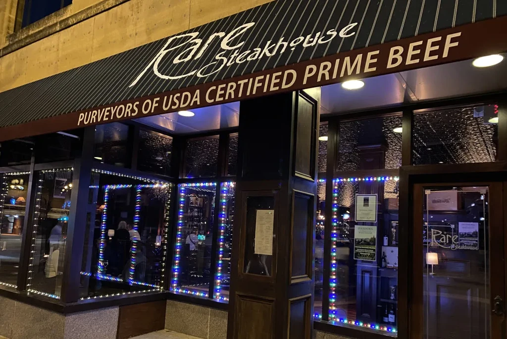 Rare Steakhouse exterior at night, windows outlined with colorful string lights.