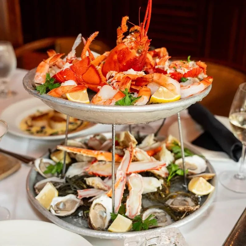 Two-tiered seafood tower with lobster, shrimp, oysters, and crab.