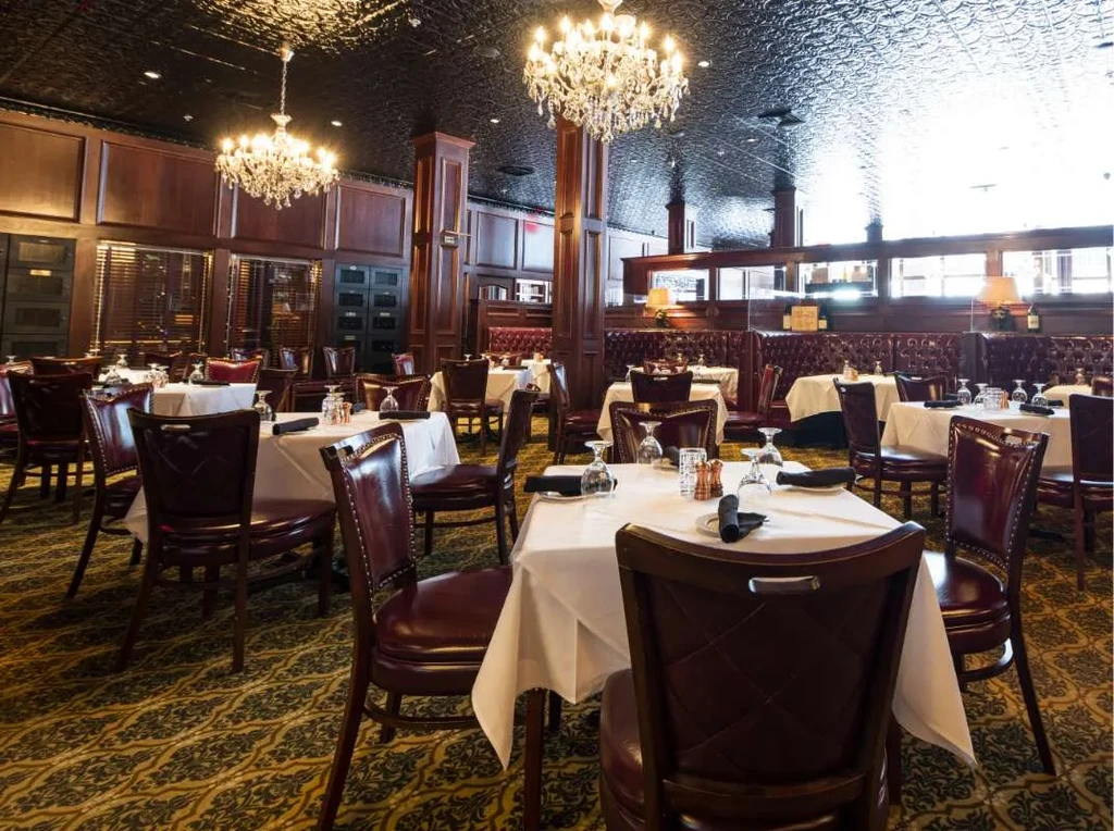 Elegant fine dining restaurant interior with set tables and crystal chandeliers.