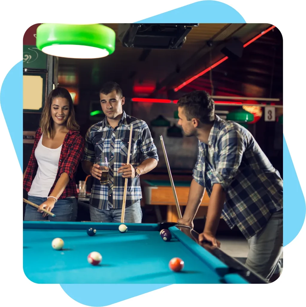 Two men and a woman playing pool in a dimly lit bar.