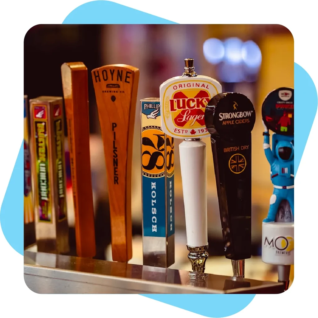 Six distinct beer and cider tap handles on a metal bar.