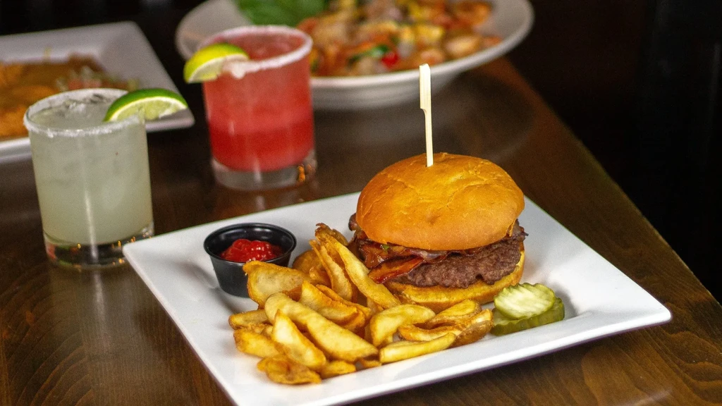 Gourmet burger, fries, ketchup, pickles, and two cocktails.