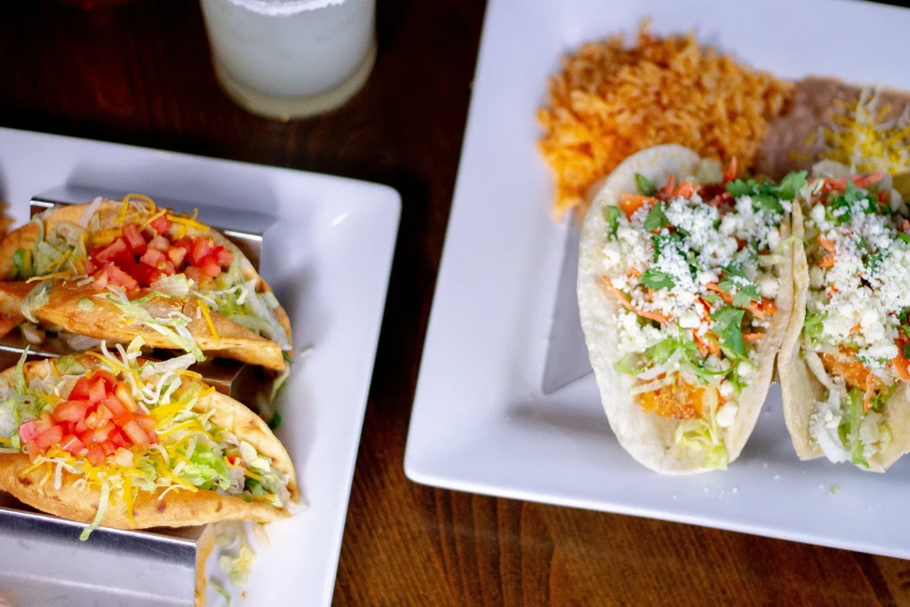 Overhead view of Mexican hard and soft shell tacos, rice, beans.