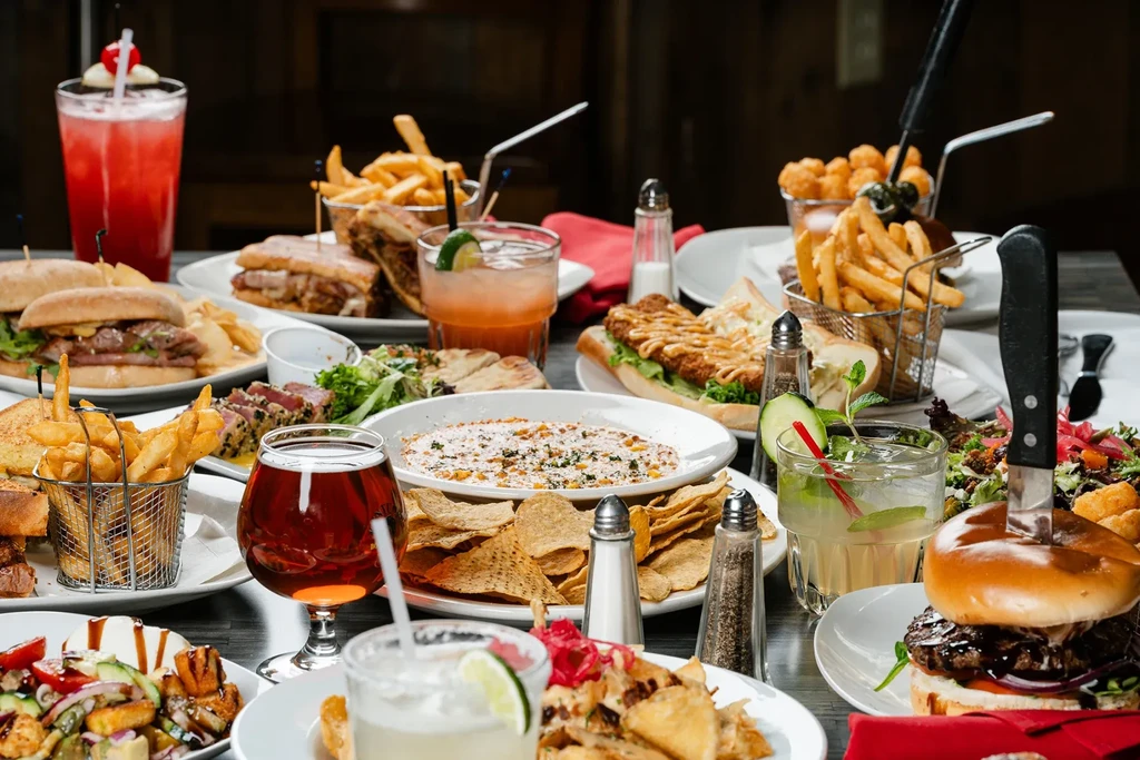 A vibrant table filled with burgers, fries, salads, and diverse cocktails.