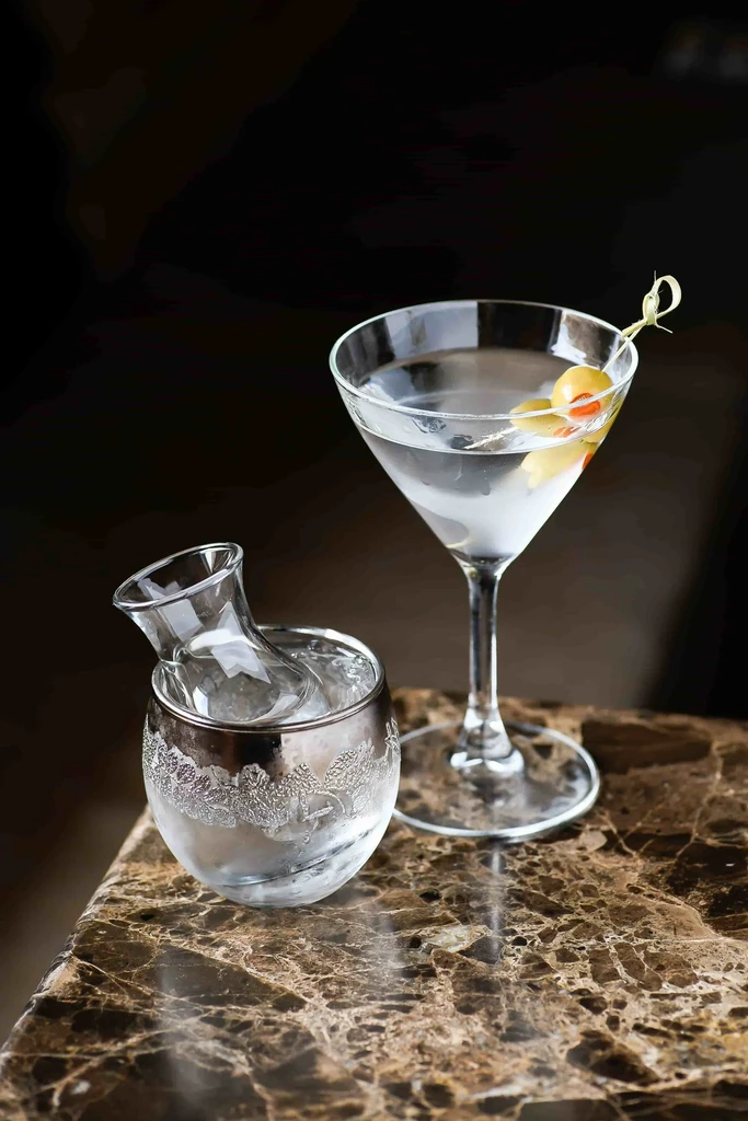 Martini and chilled sake set on a dark marble surface.