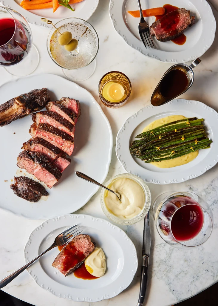 Elegant overhead view of a steak dinner with asparagus, wine, and martini.