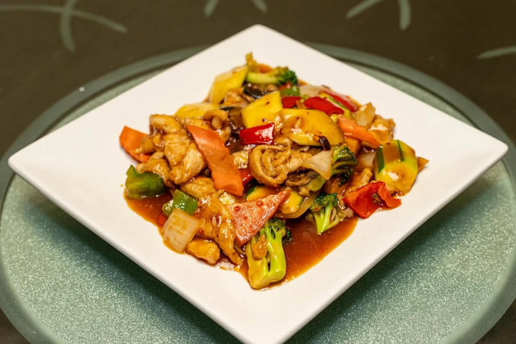 Top-down shot of colorful chicken and vegetable stir-fry on a white plate.